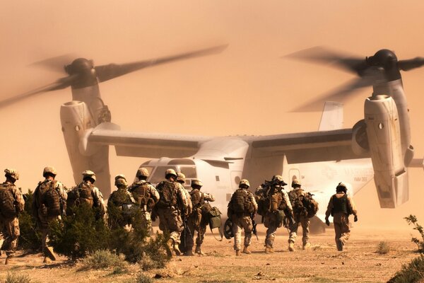 A crowd of soldiers go to the helicopter