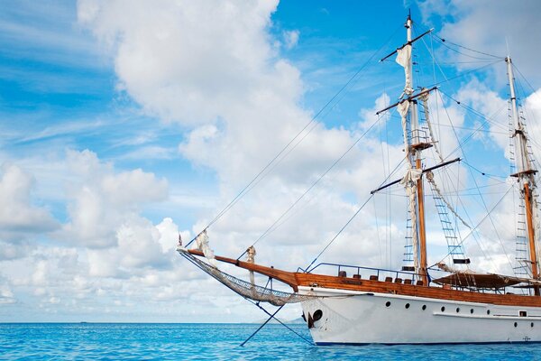 SAILBOAT IN THE SEA AGAINST THE BACKGROUND OF CLOUDS