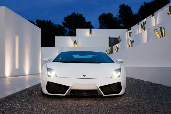 Une Lamborghini blanche se dresse à côté des murs blancs