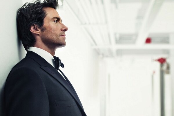 Hugh Jackman en smoking au mur blanc