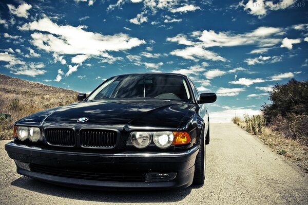 Black BMW on the background of the sky with clouds