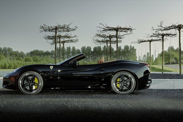 Une ferrari noire sans conducteur se tient sur la route