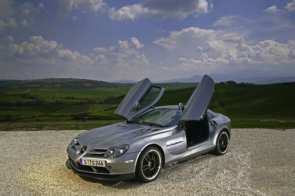 Mercedes mit nach oben öffnenden Türen vor dem Hintergrund von Bergen und Wolken