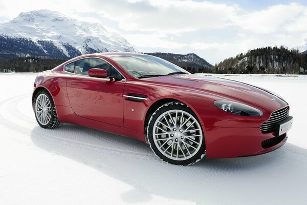 Coche rojo en el fondo de las montañas en la nieve