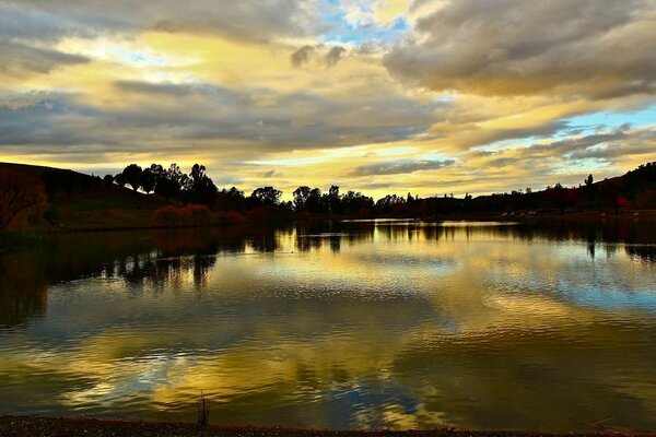 Puesta de sol con nubes en un lago tranquilo