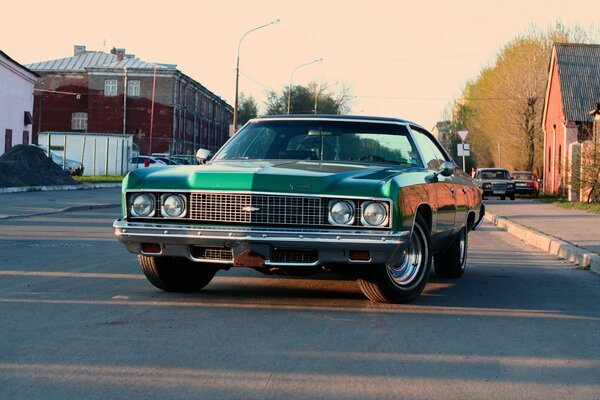 Chevy impala 1973 green on the road in the town