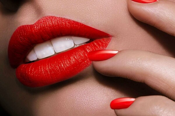 Unghie rosse, denti bianchi abbaglianti su sfondo rossetto rosso