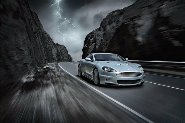 La voiture aston martin roule à grande vitesse sur une route de montagne