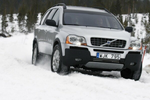 A white Volvo in the middle of a snowy road