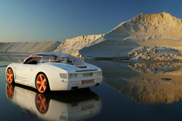 Ein weißer Sportwagen steht auf dem getauchten Eis vor dem Hintergrund eines Hügels aus Schnee und Eis