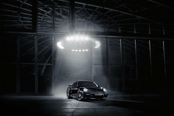 Black Porsche in the garage with a directional light on the car