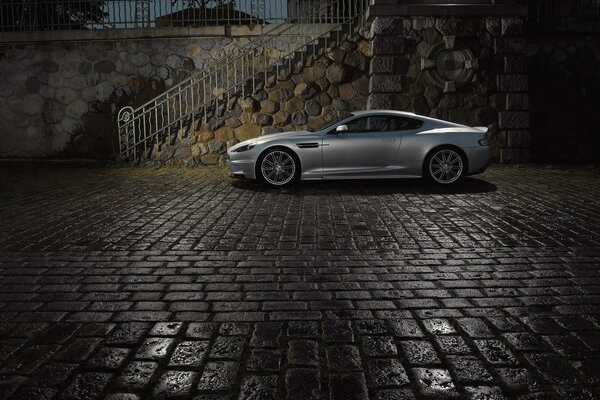 Aston Martin is standing near the stairs on the cobblestones