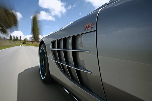 A silver Mercedes is driving on the road