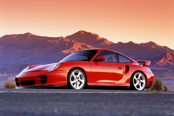 Red Porsche on the background of sunset mountains
