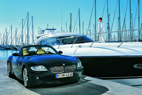 BMW junto a un yate elegante con un hombre a bordo