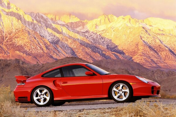 Voiture rouge dans les montagnes au coucher du soleil