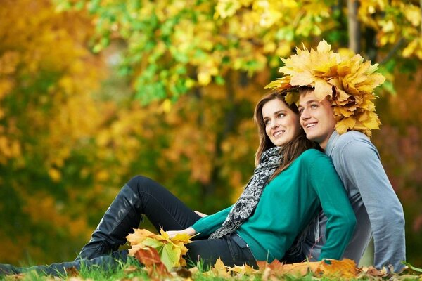 A young couple in the autumn forest with a wreath of maple leaves