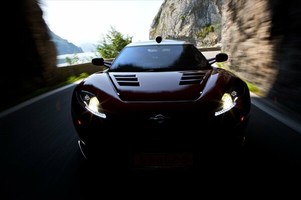 The car drives into the tunnel with its headlights on