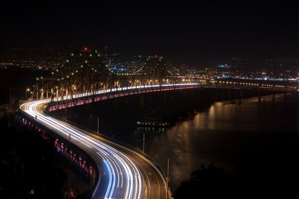 Die Straße entlang der Brücke über den Fluss in der Nacht