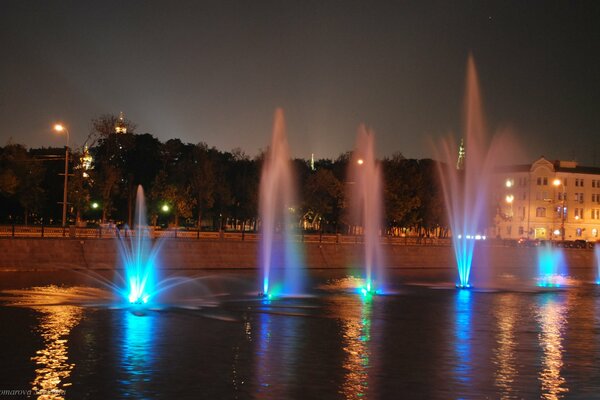 Fontaines LED sur la rivière au milieu de la ville du soir