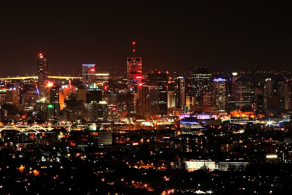 Vista de las luces de la ciudad nocturna desde lo alto de un rascacielos de varios pisos