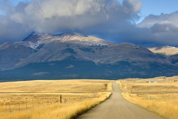 Road, mountains and autumn fields