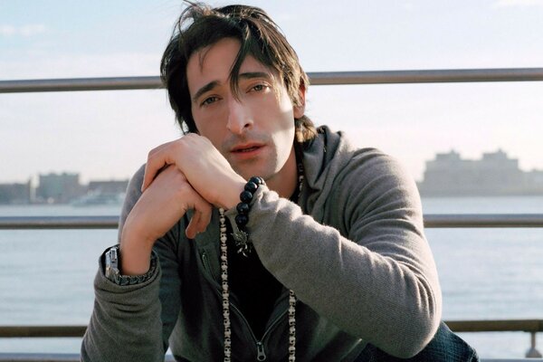 Adrian Brody siedzi na tle wody