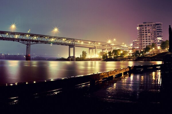 Blick in der Nacht auf die Brücke mit brennenden Lichtern am Fluss