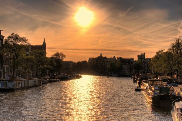 Sunset over Amsterdam river boats and sun