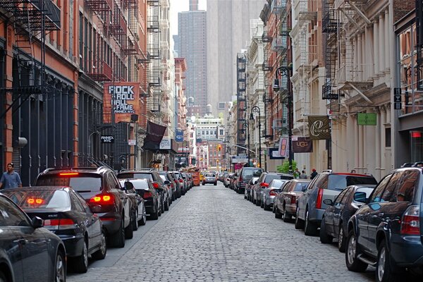 The street of the metropolis during the day. lots of cars on the side of the road