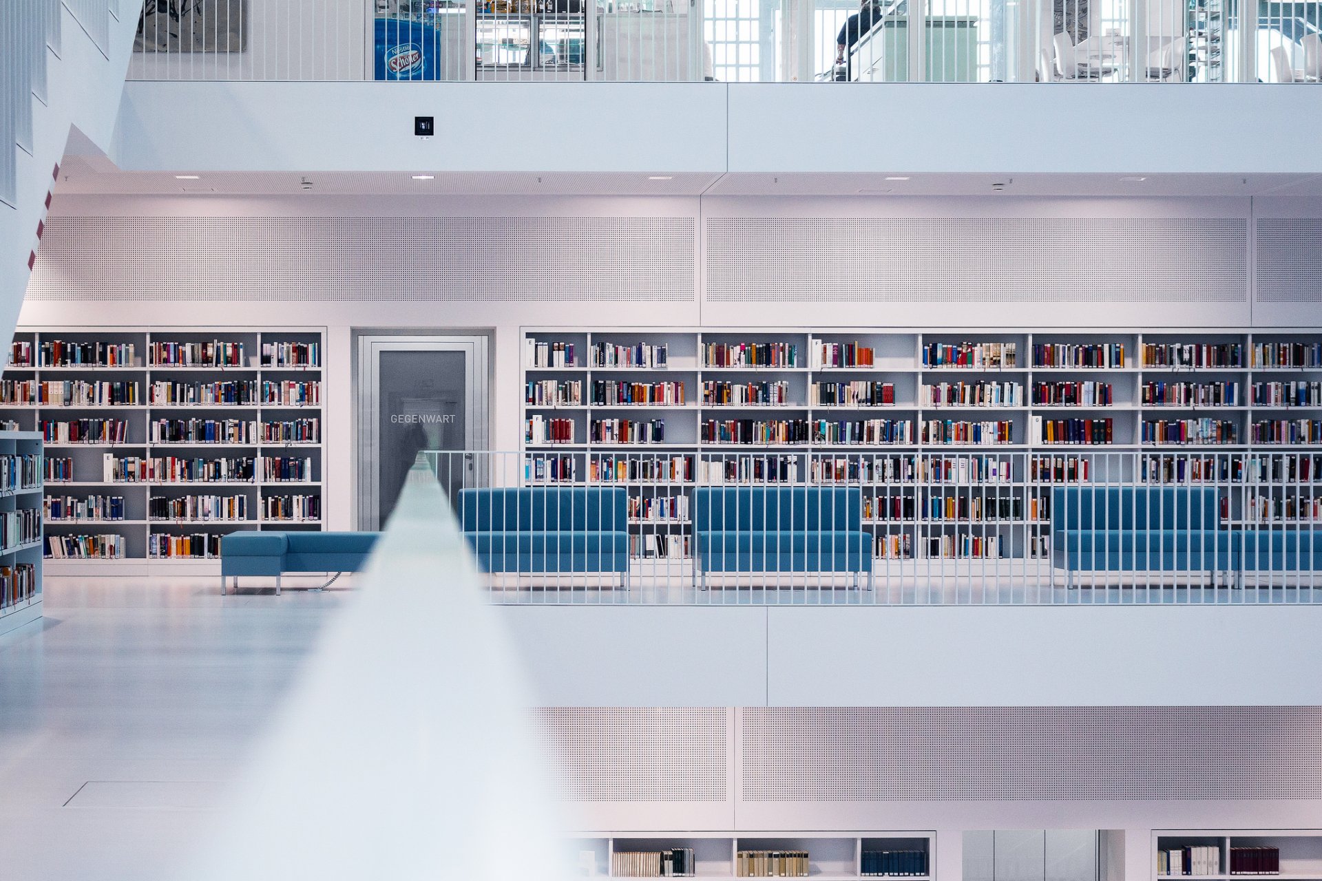 biblioteca libros piso barandilla escaleras sofá persona comedor habitación