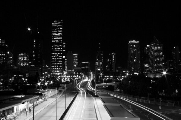 A black-and-white road illuminated by the lights of a big city