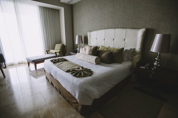 Спальная комната с большой кроватью и много подешек на кровате