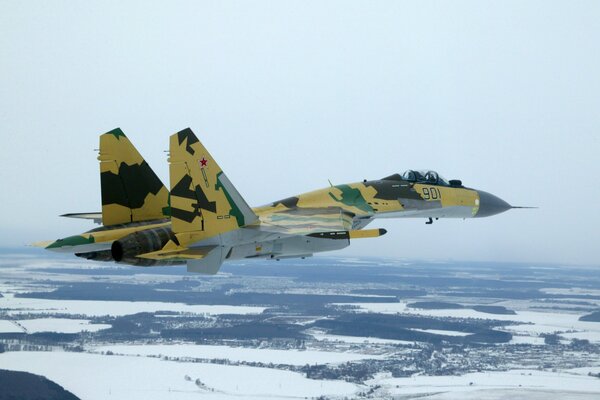 A fighter jet flies in the sky in winter