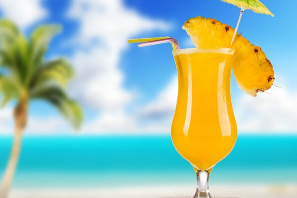 A glass of pineapple cocktail on the background of the beach