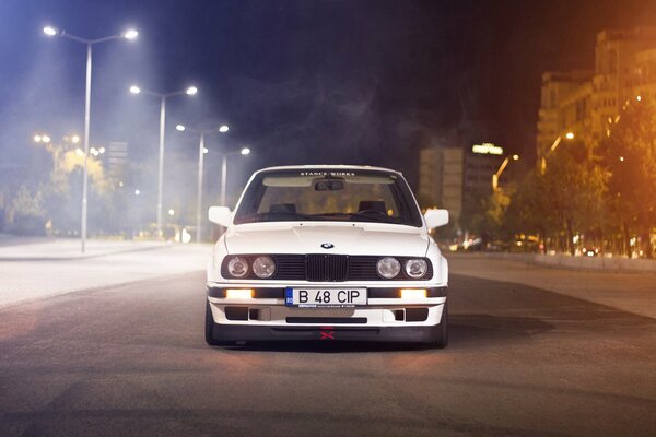 Białe BMW na środku drogi w nocy