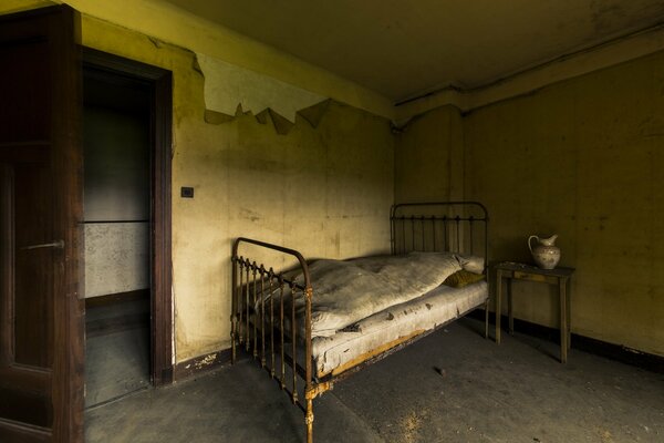 Старая кровать в комнате с открытой дверью