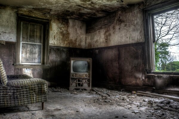 Schmutziges verlassenes Zimmer mit Sessel und Fernseher