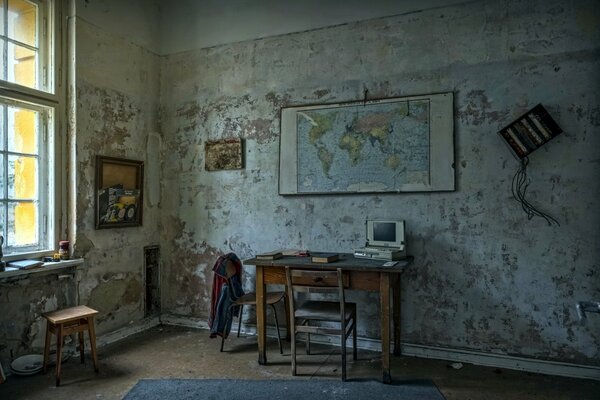 An old room with a table and chairs near the map on the wall