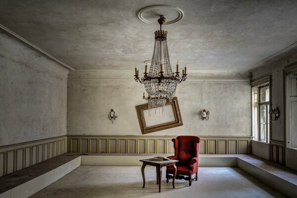A low-hanging chandelier in the middle of an almost empty room