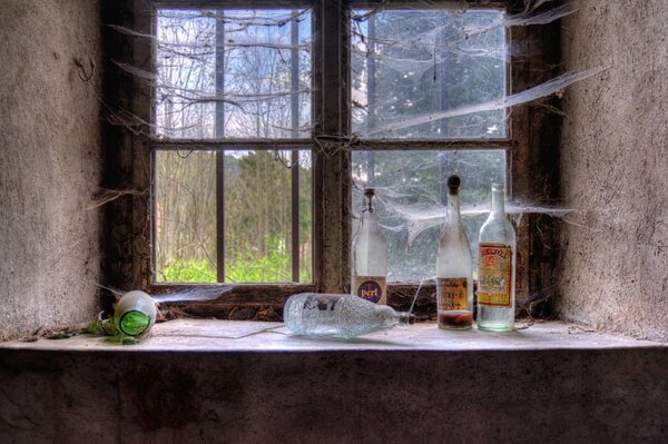 Botellas en la ventana con telarañas