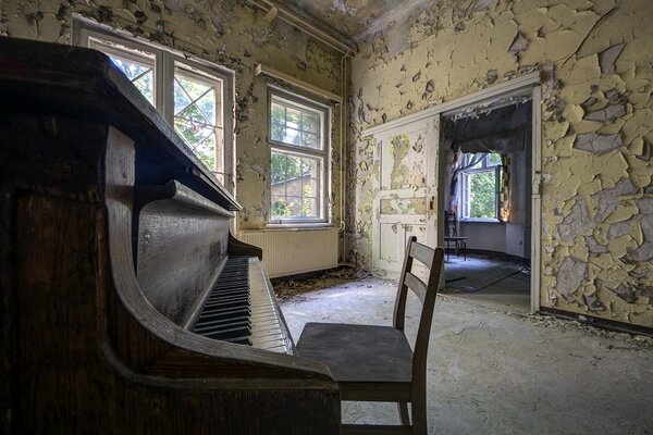 An abandoned room with a chair near the piano