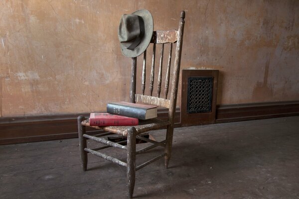 Stos książek leży na starym krześle z kapeluszem