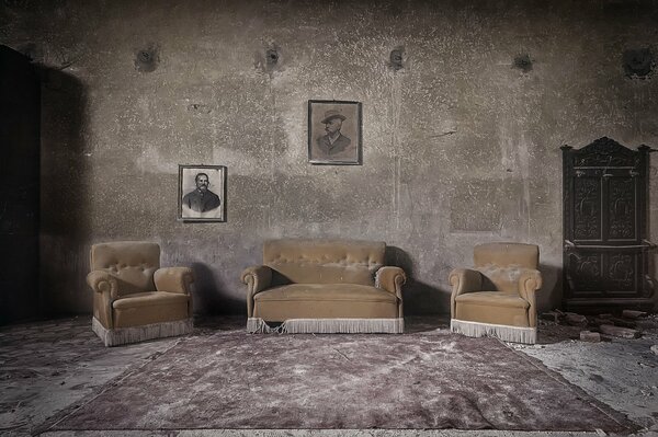 An old room with a sofa and portraits on the wall