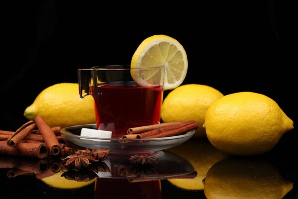 Una taza de té con limones, palitos de canela, un baño y refinados