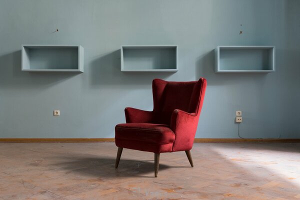 A red armchair on the background of a blue wall