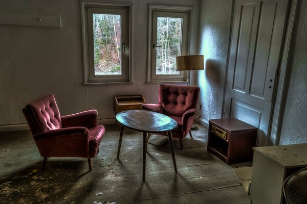 A small room with armchairs, a chest of drawers and a small round table