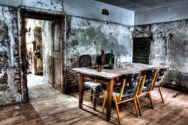Sala da pranzo abbandonata con grande tavolo e sedie