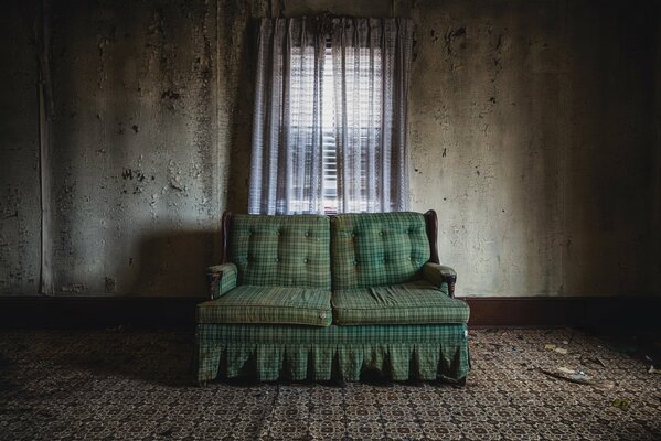 An empty room without wallpaper, a lonely green armchair