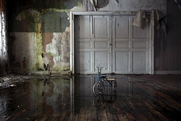 Пустая комната без обоев, посередине стоит велосипед, двери полностью закрыты
